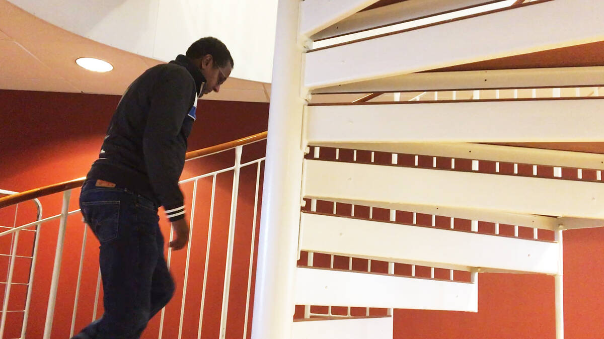 En ensam man går med tunga steg upp för en trappa.