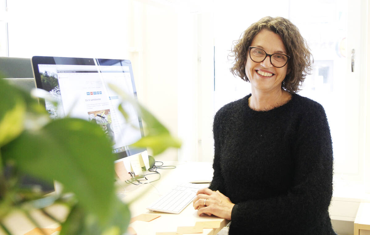 Glad medarbetare vid sitt skrivbord.