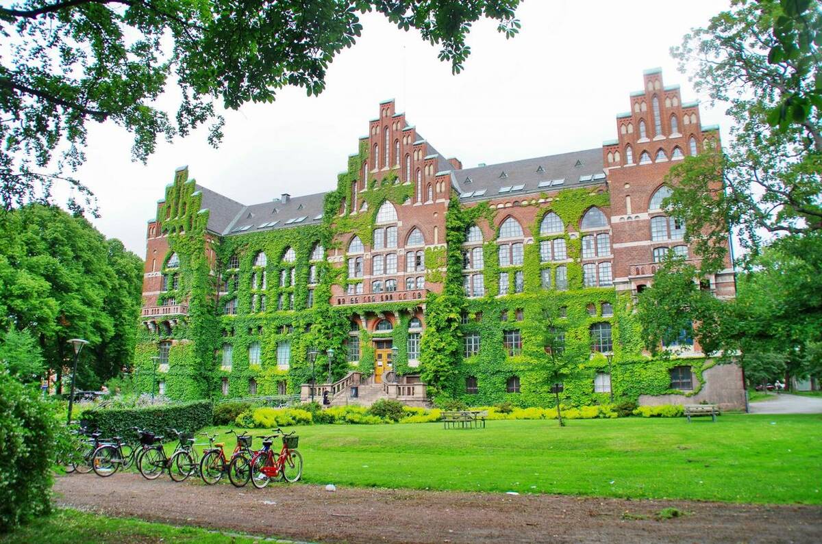 Vacker gammal universitetsbyggnad täckt av grönska.