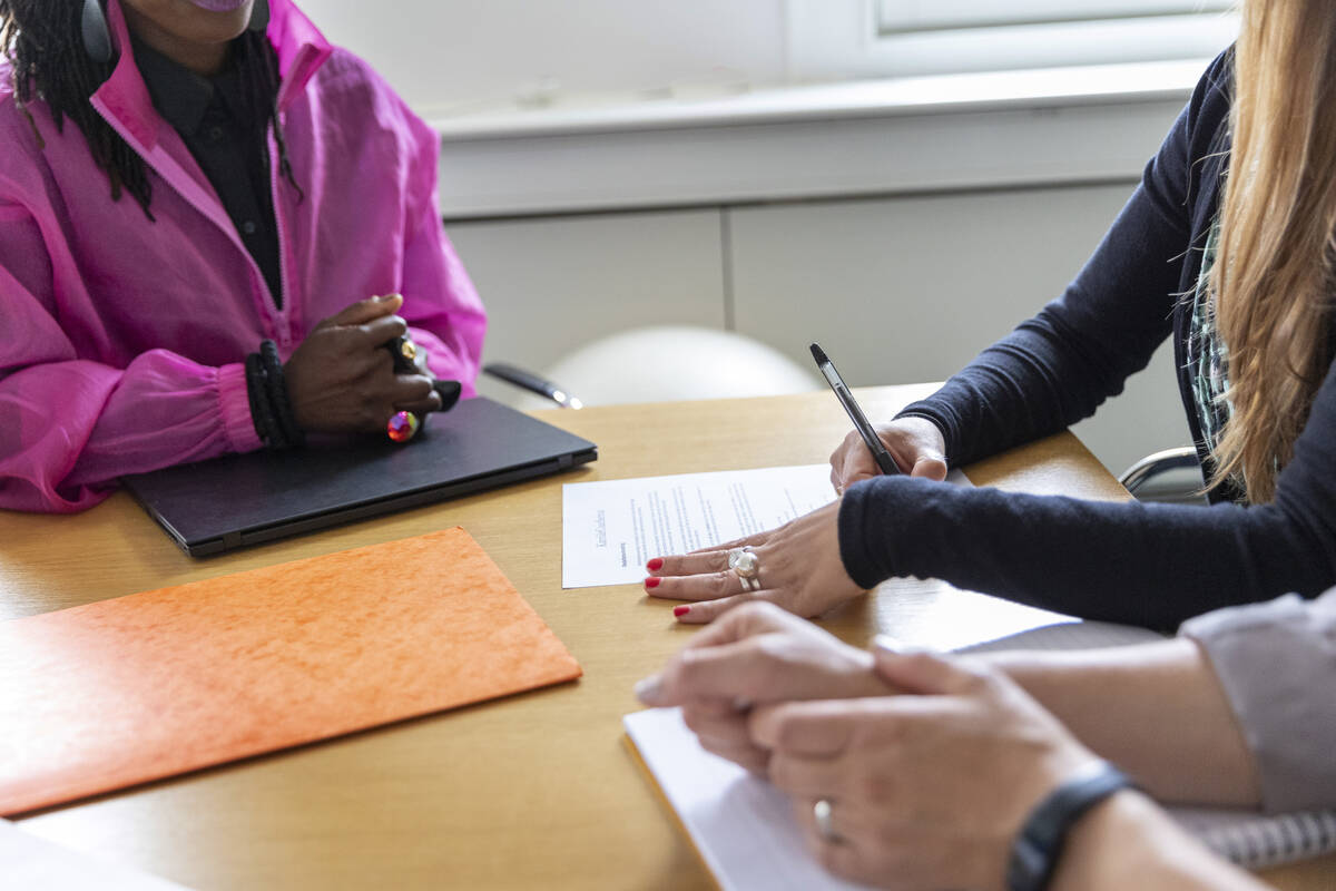 Tre kvinnor som skriver under papper vid ett konferensbord.