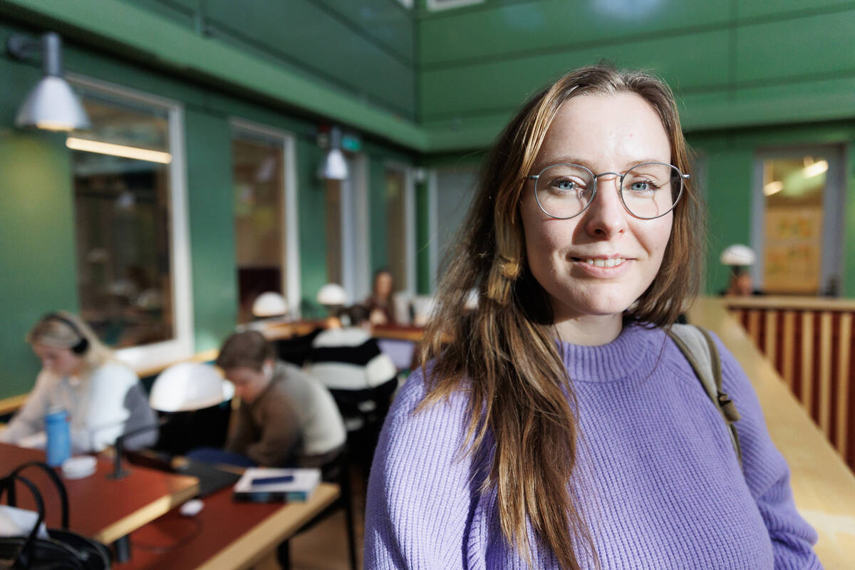Trevlig, smart ung kvinna på ett universitetsbibliotek.