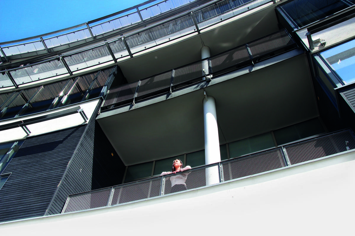 Intervjupersonen på en balkong på en universitetsbyggnad.