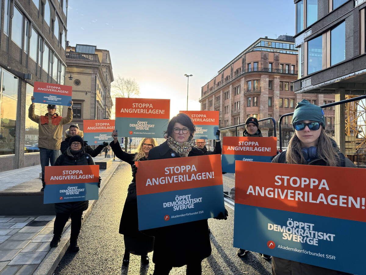 Förbundsordföranden och andra personer står med plakat med texten Stoppa angiverilagen