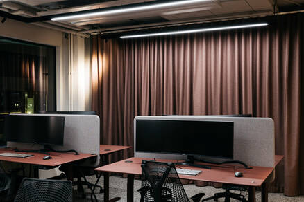 Kontorsmiljö av mer klassisk stil med landskap. Stora dataskärmar och mörkare jordfärger i färgpaletten på väggar och gardiner.